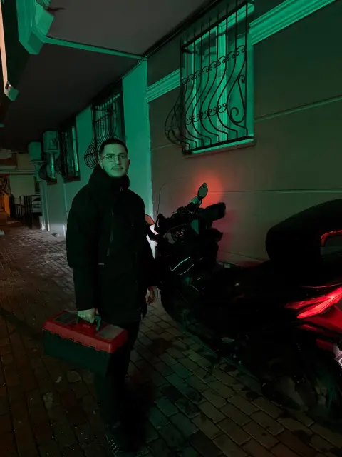Usta gece bir binanın önünde, elinde alet çantası
